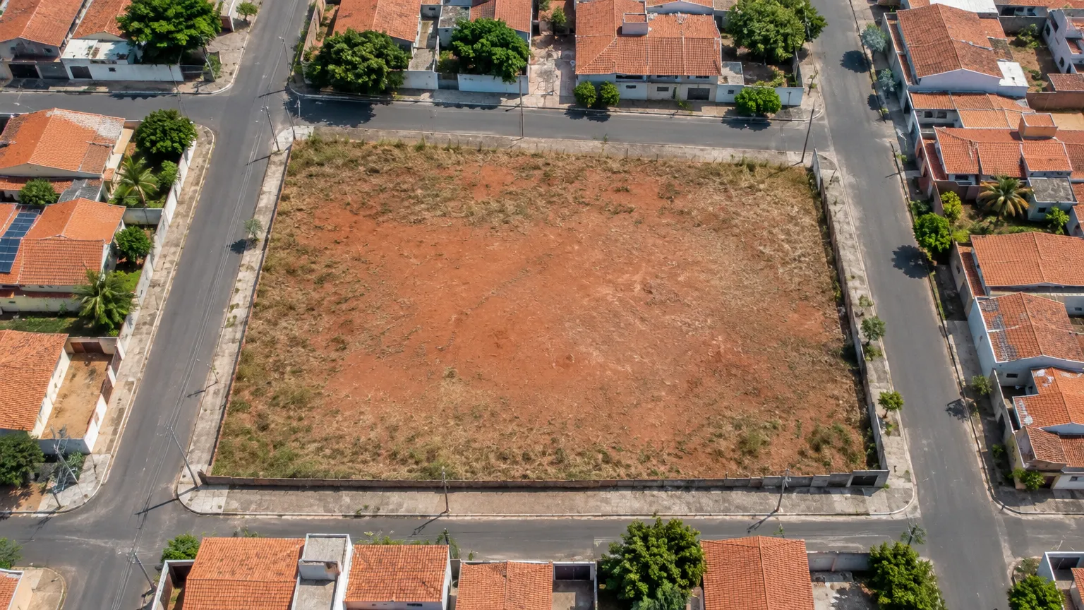 Vista de cima de um terreno vazio cercado por ruas e casas, com a divisão dos lotes desenhada por cima